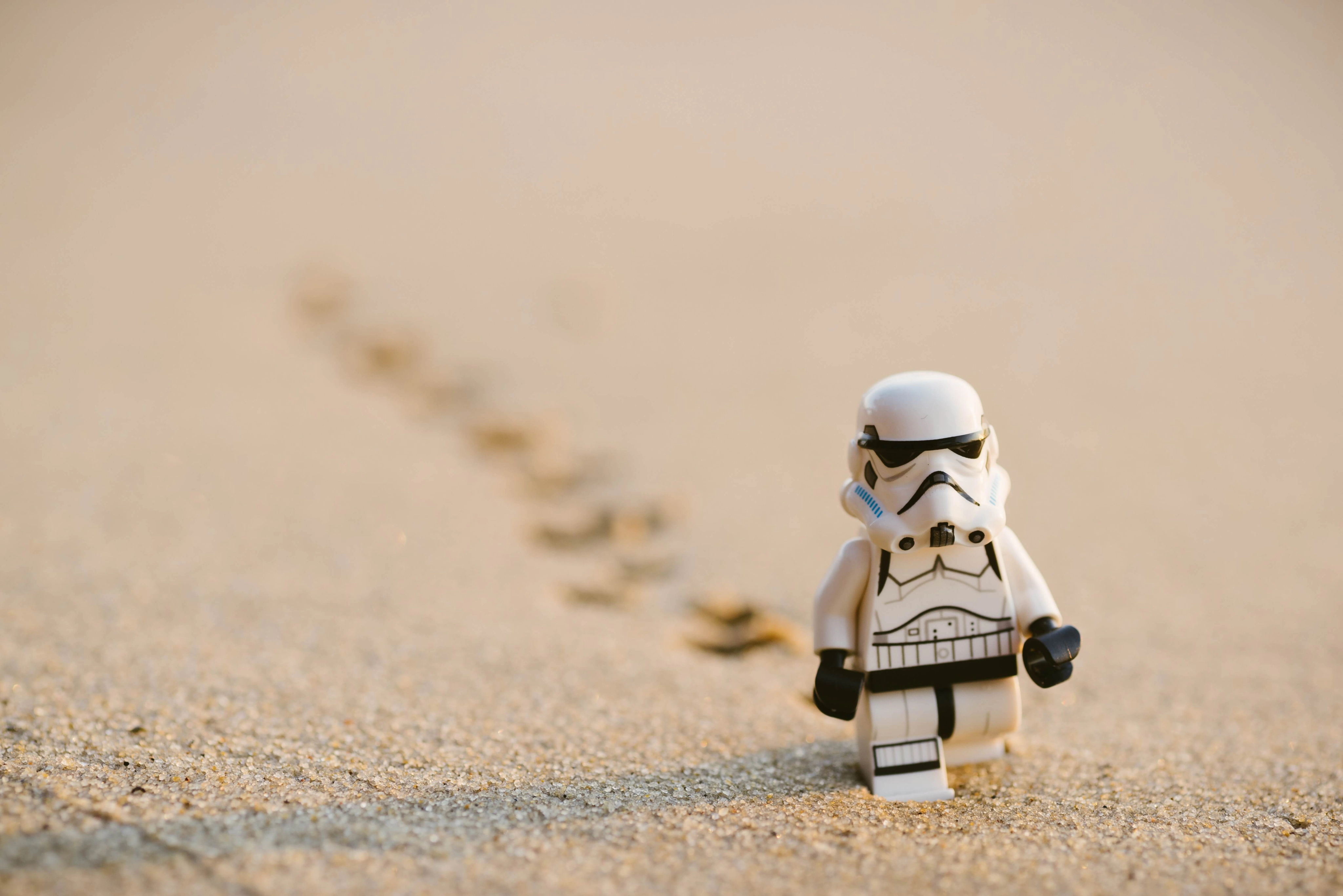 A lego stormtrooper walking across the dessert.
